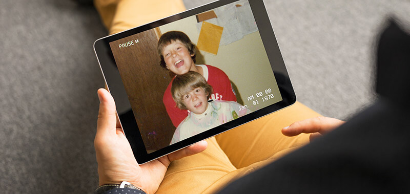 Family watching digitized home video playback on a tablet after video transfer and preservation service