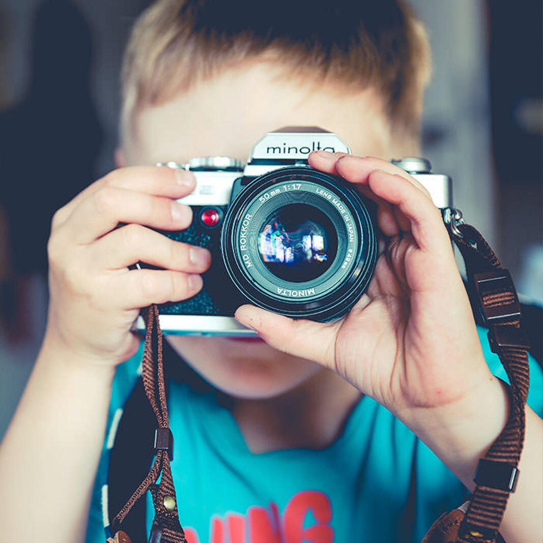 Child holding a camera up to their face taking a photo