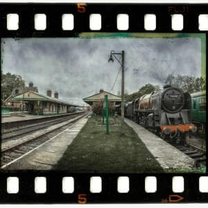 Scanned film negative frame showing a vintage train at a station after digitization