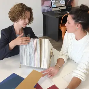 Customer consulting with framing specialist while reviewing mat board and framing material samples