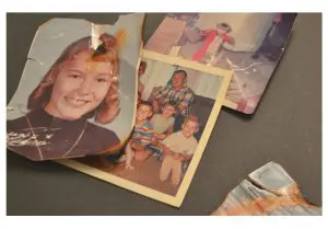 Torn and water-damaged family photographs laid out for photo restoration
