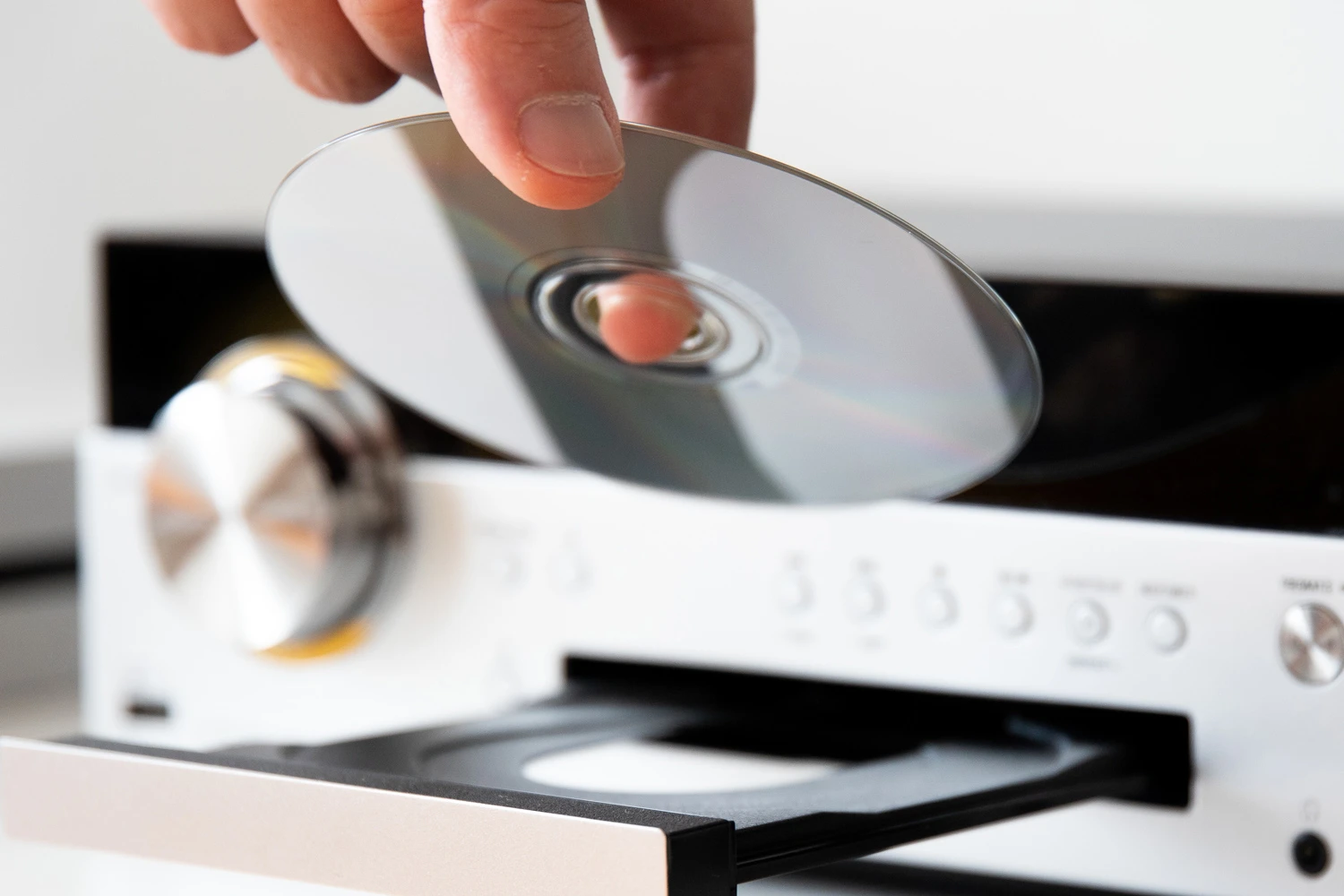 A person inserting a DVD into a disc drive, highlighting the process of DVD duplication or playback