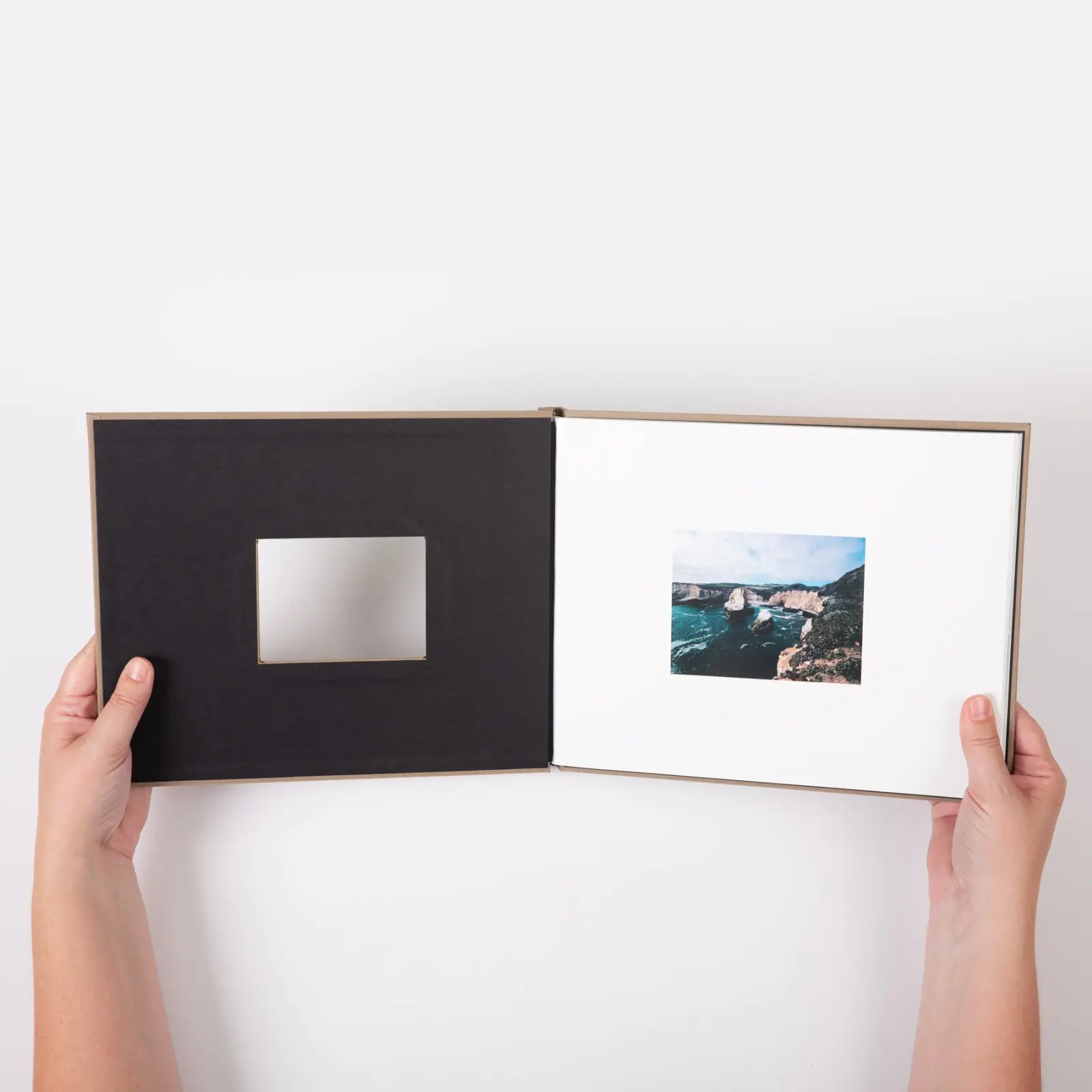 Person holding an open photo book with a window in the cover