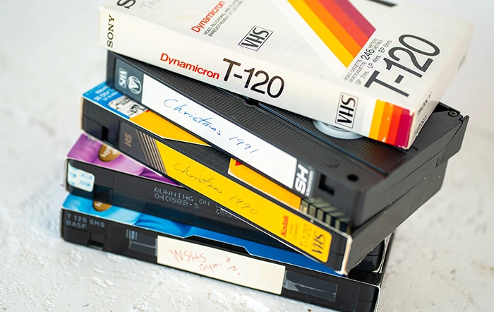 Stack of old VHS tapes ready for video transfer and digitizing at The Camera Shop Muskegon