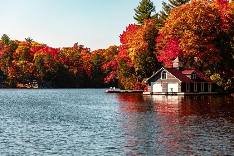 Lakeside boathouse surrounded by colorful autumn trees reflecting on water