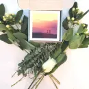 Roses next to Dutch & Deckle Gratitude Cards in box with picture of sunset, palm trees and water.