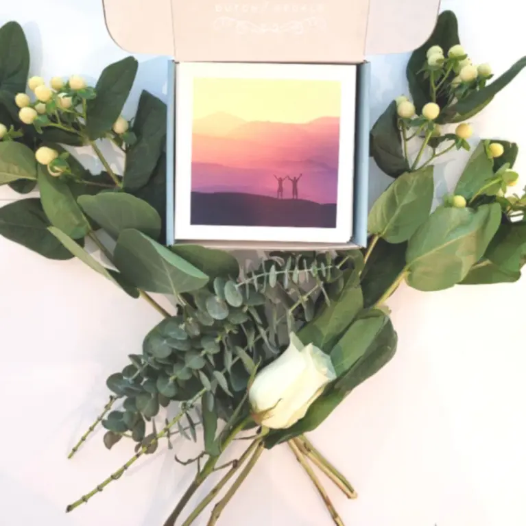 Roses next to Dutch & Deckle Gratitude Cards in box with picture of sunset, palm trees and water.