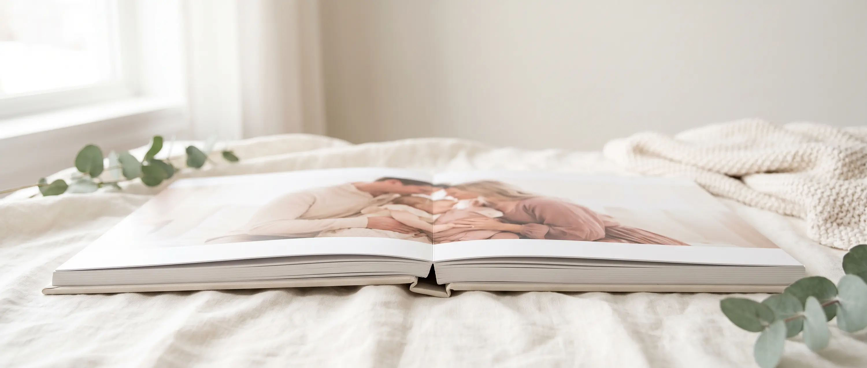 Layflat photo book open on a bed showing a seamless panoramic spread