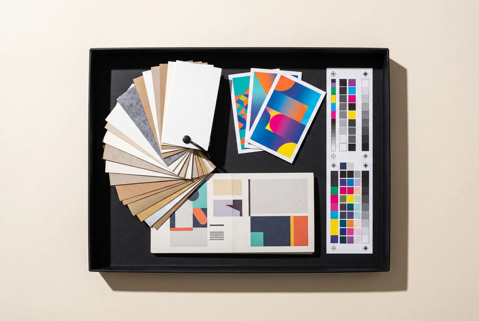 Open black sample kit box with paper swatches, printed sample cards and a color test strip.