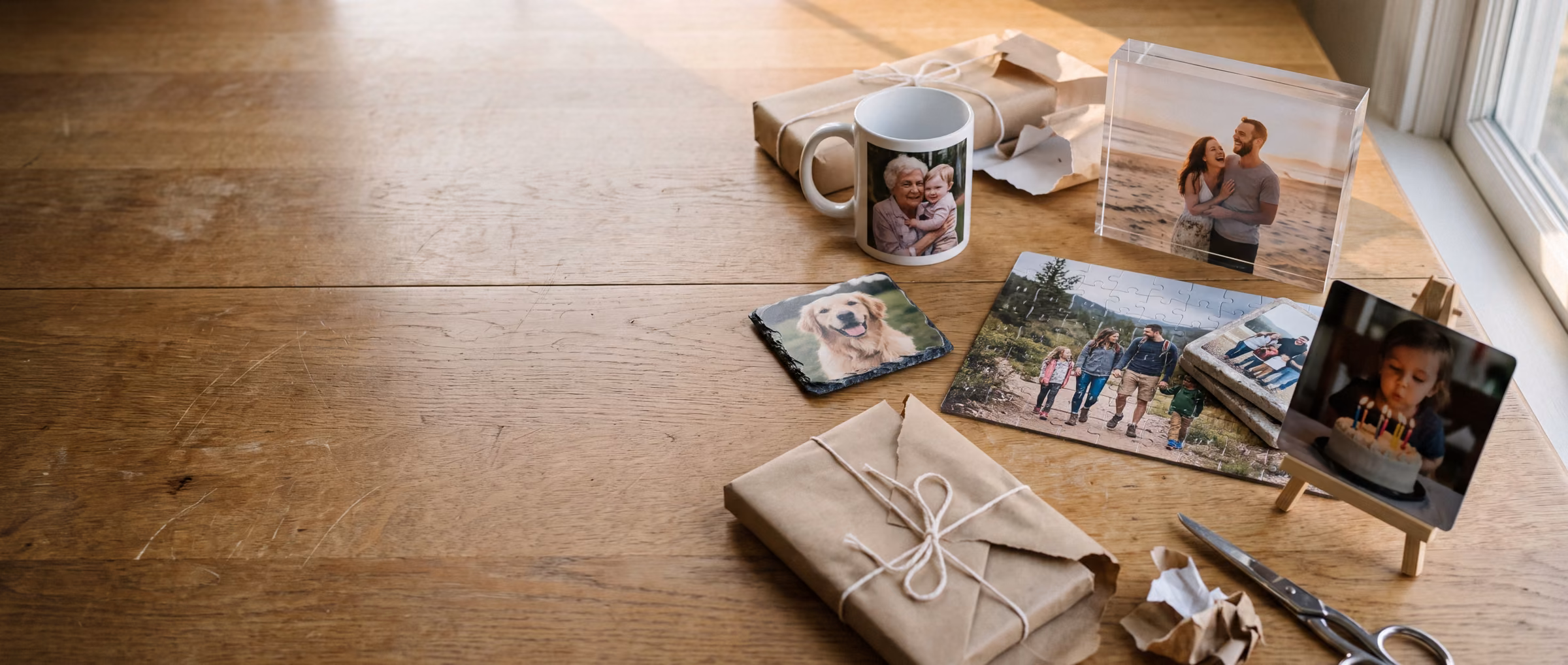 Personalized photo gifts on an oak table: a mug, slate, acrylic block, puzzle, coasters and a metal desk print