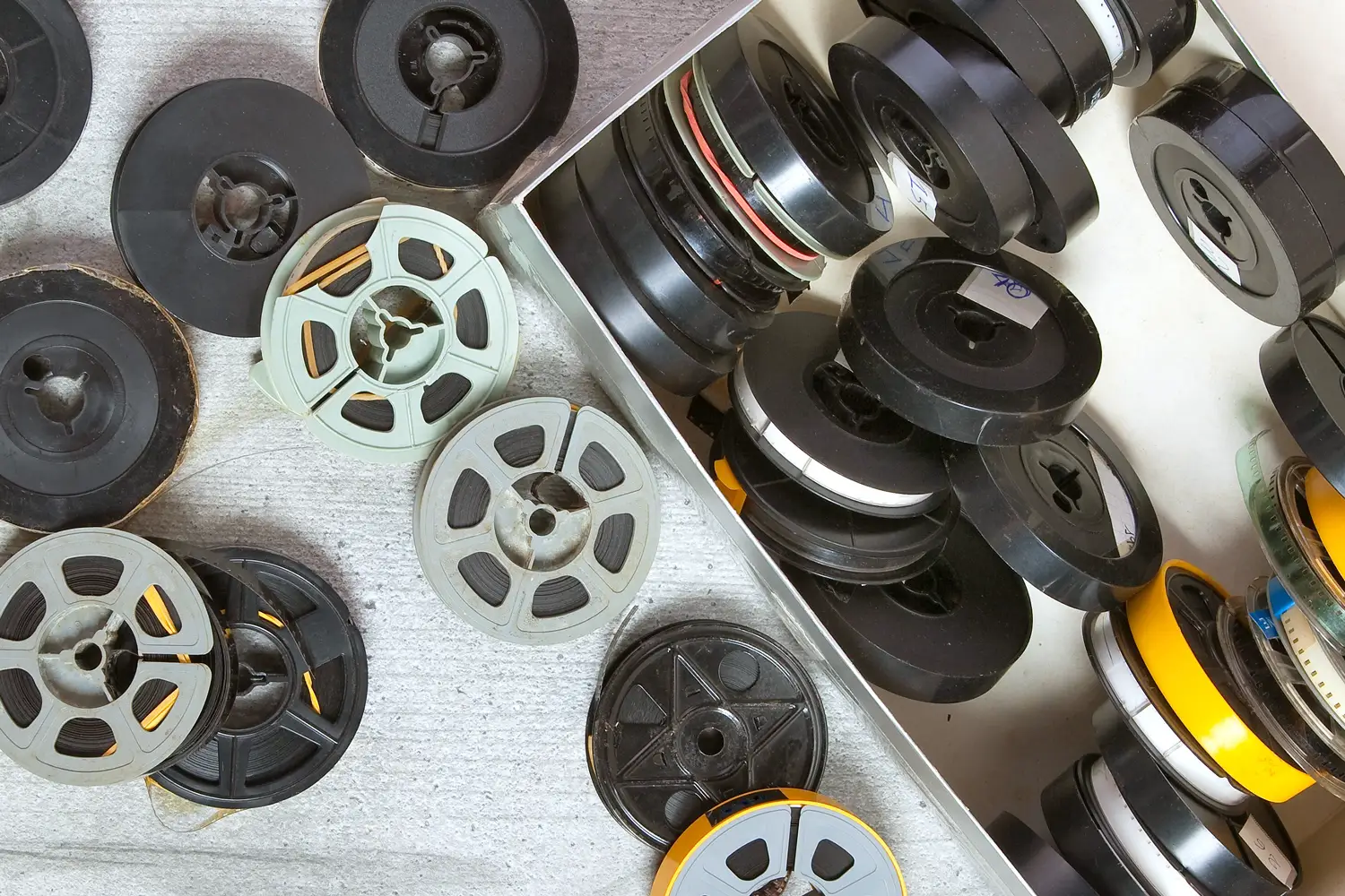 A collection of vintage movie film reels in various sizes and colors, representing film digitization and archival services