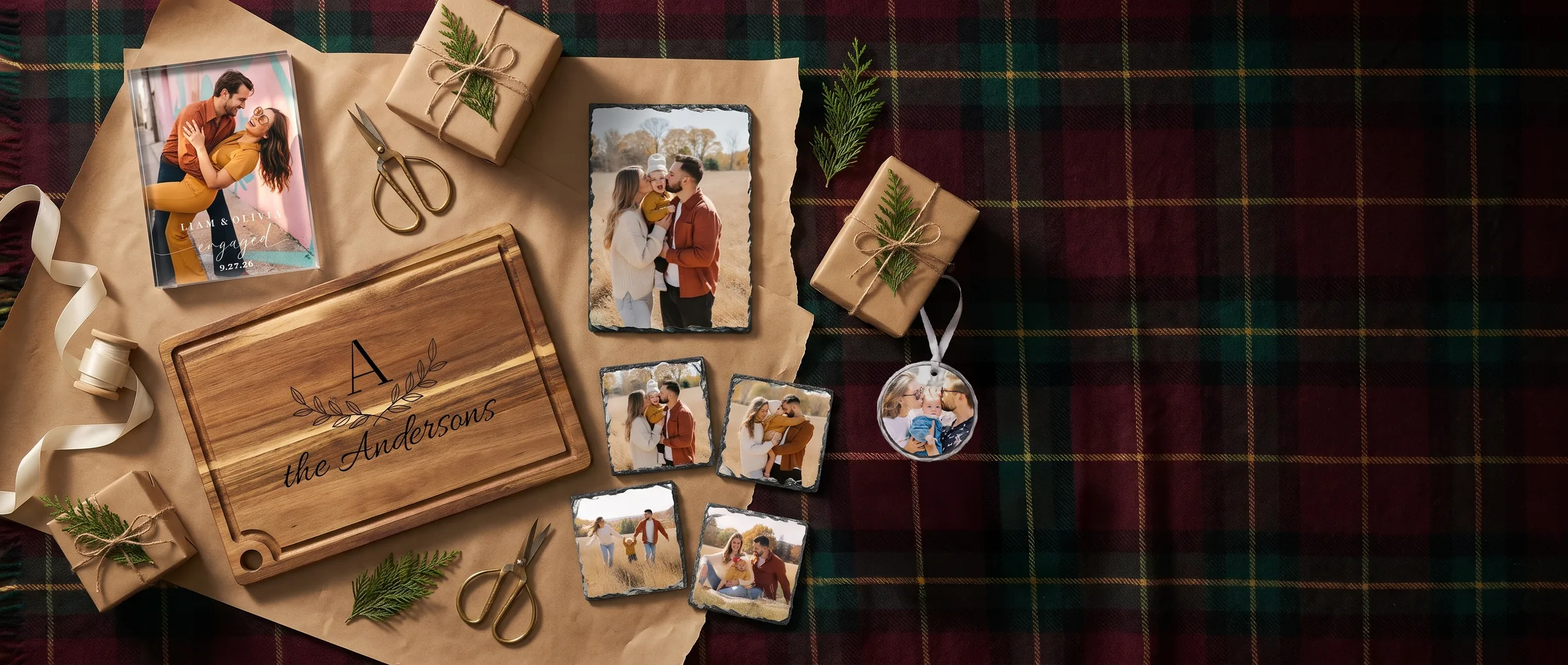 Personalized photo gifts laid out on a tartan blanket for wrapping: acrylic photo block, engraved cutting board, photo slate, slate coasters and a crystal ornament