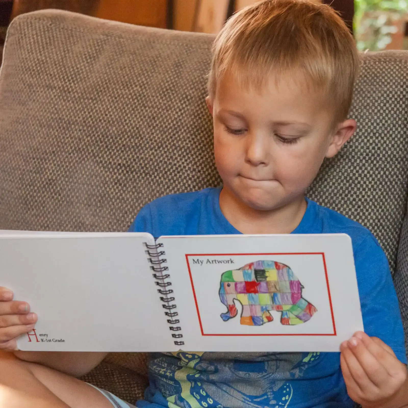 Boy looking at 5x7 spiral photo book of his artwork
