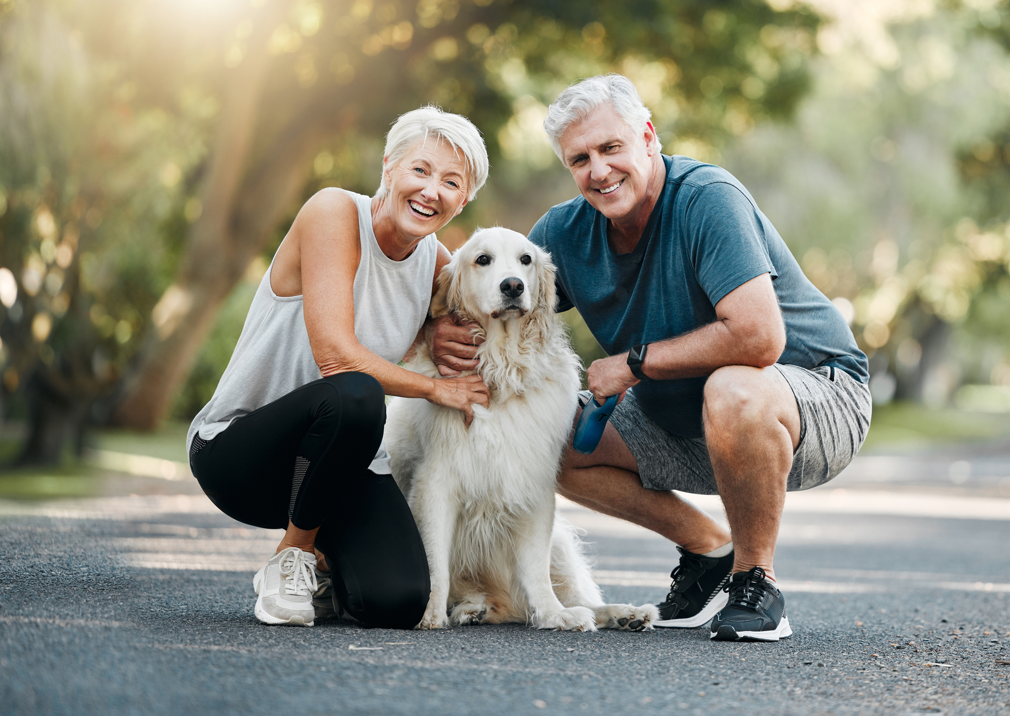 Happy older adults enjoying a walk with their dog.