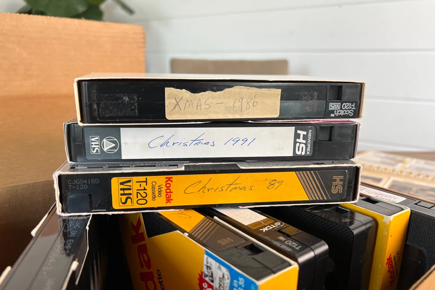 A stack of labeled VHS tapes from past decades, illustrating video tape transfer services to preserve old memories in digital format
