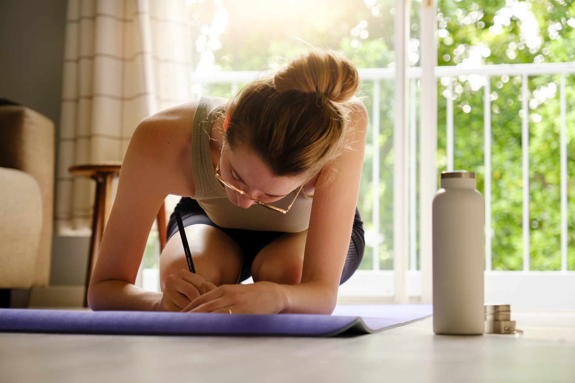 A person writing in their fitness journal before doing a morning yoga session. 