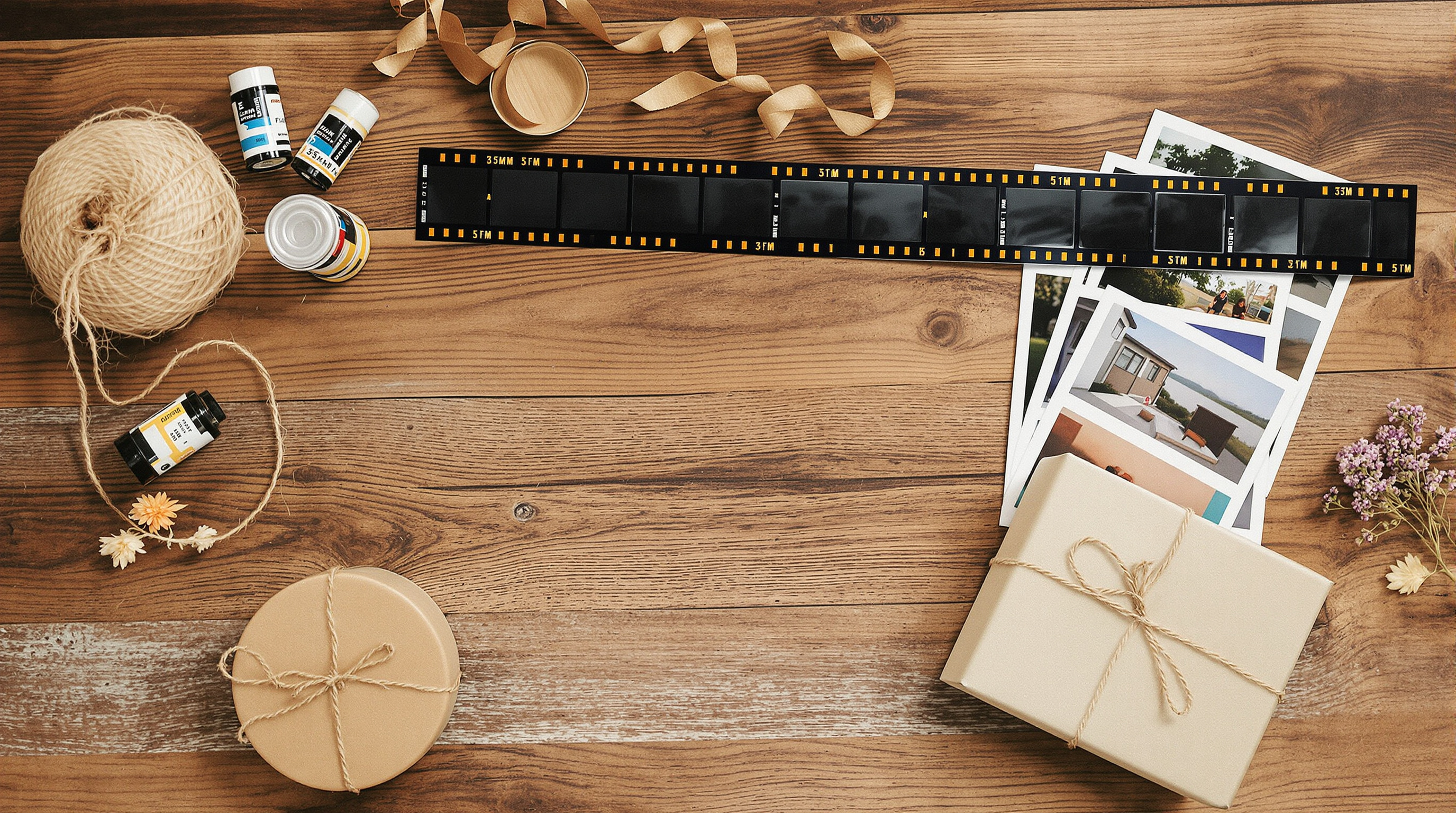 Vintage 35mm film canisters, film negatives, printed photos, and gift box on rustic wood surface in Louisville, Kentucky