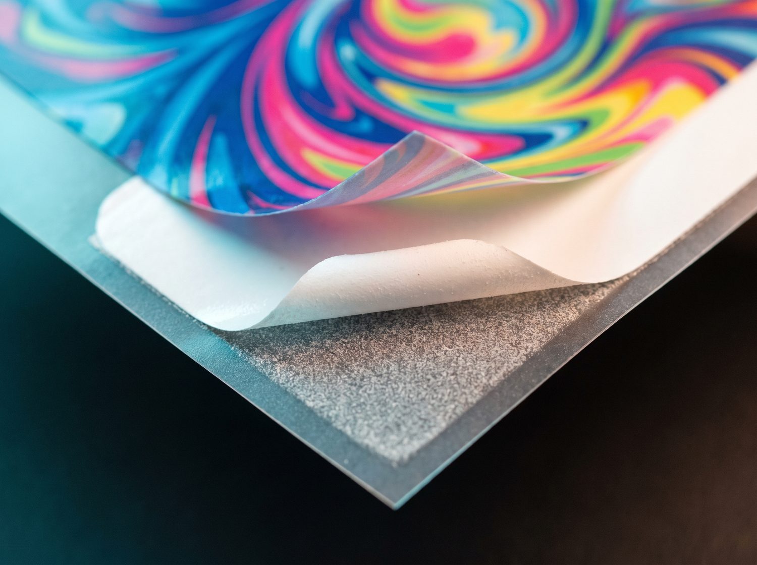 Macro view of a DTF transfer peeling back, showing the colour layer, the white ink underbase and the clear carrier film