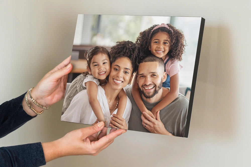 A person holds a studio block photo print featuring a smiling family, showcasing its thick, sturdy design with a sleek black edge