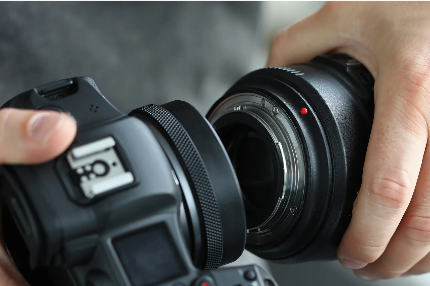 Close-up of a person attaching a camera lens to a DSLR body, emphasizing precision and care in handling professional photography equipment