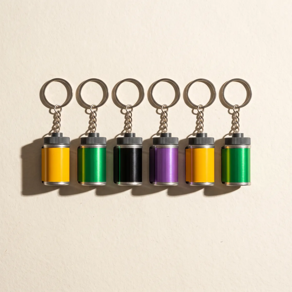 Row of 35mm film canister keychains in classic film stock colors.