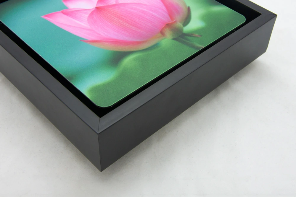 A close-up of a framed metal print featuring a vibrant pink lotus flower, set in a sleek black float frame