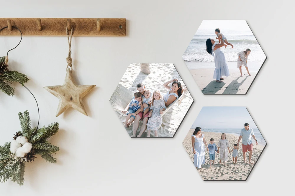 A set of hexagonal wall tiles featuring beach family photos, arranged on a light-colored wall near rustic holiday decor