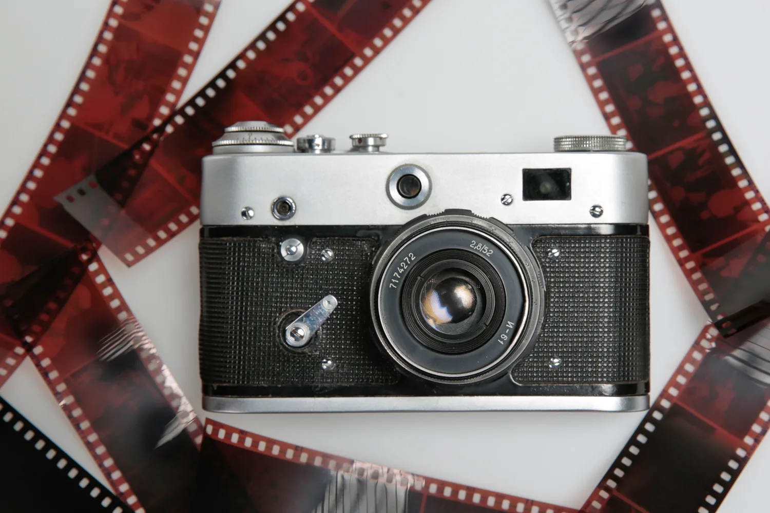 A vintage film camera surrounded by developed 35mm film negatives, representing analog photography and film processing