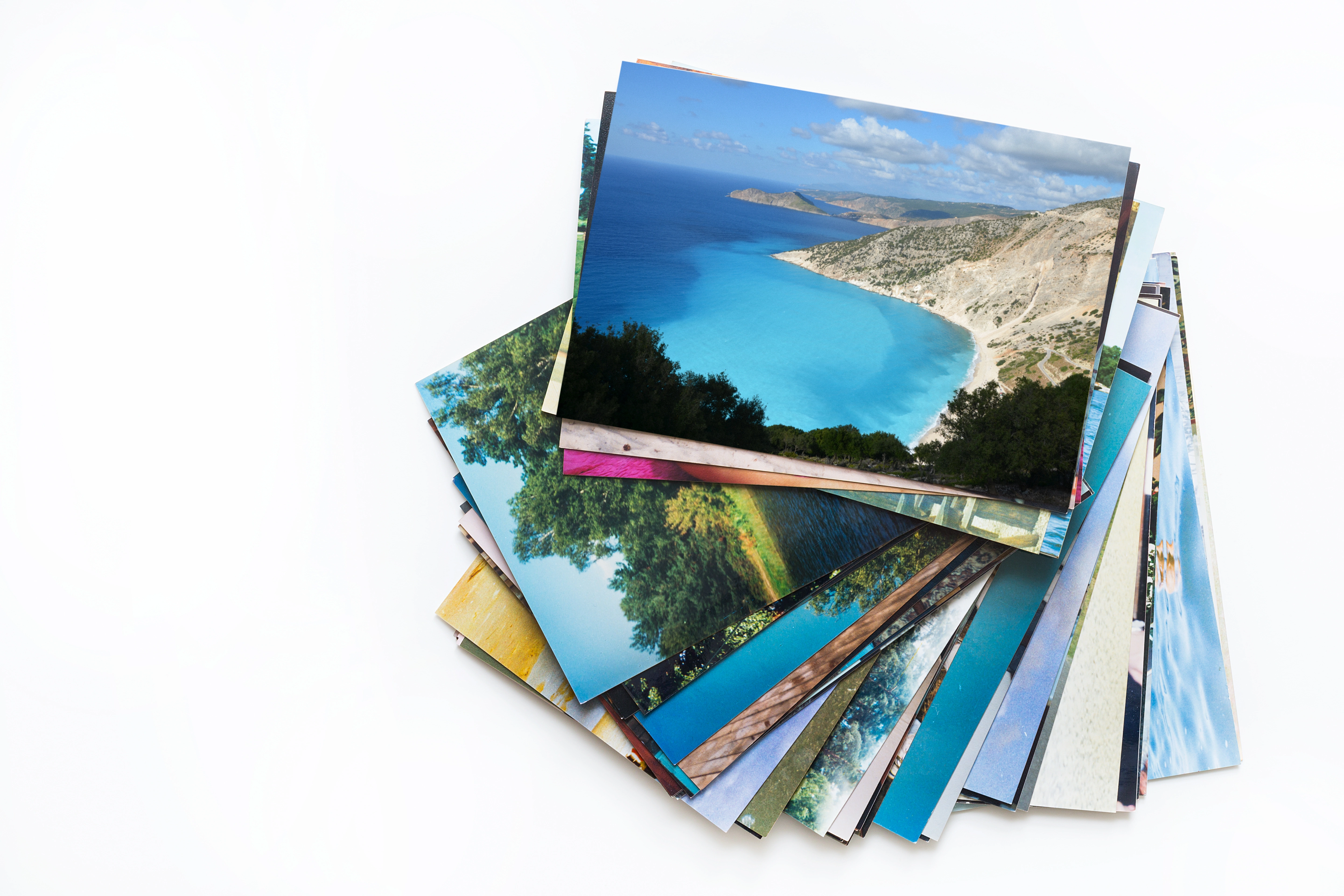 A fan-shaped stack of printed photos from various vacations.