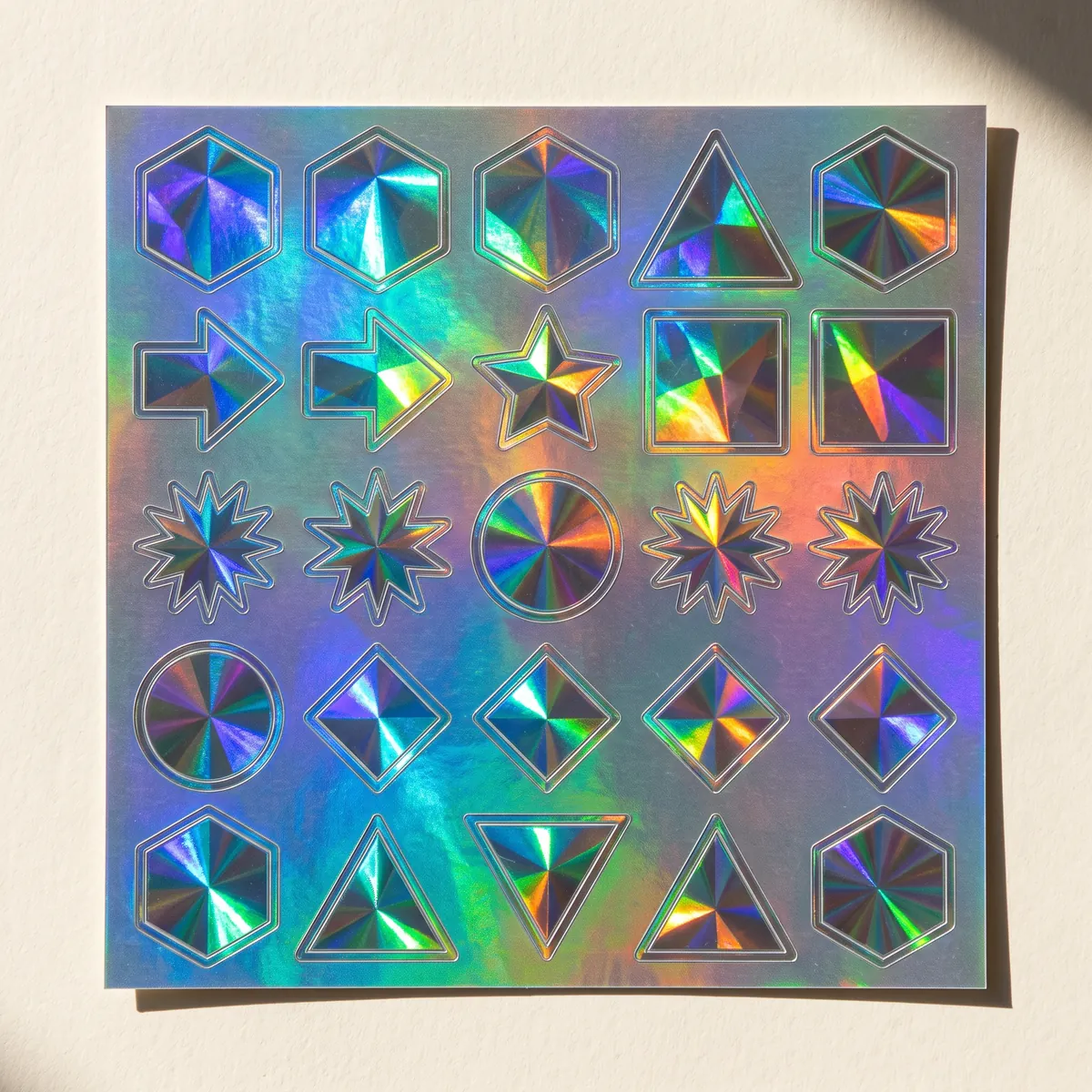 Holographic vinyl sticker sheet catching prismatic light.