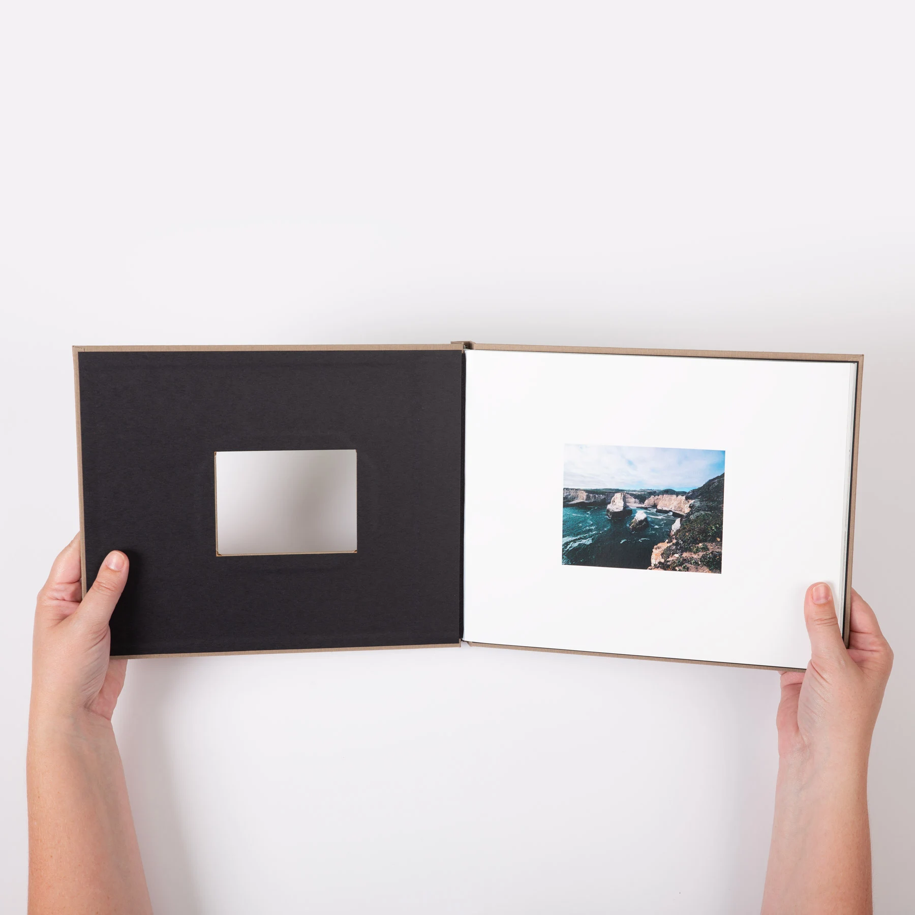 Person holding an open photo book with a window in the cover