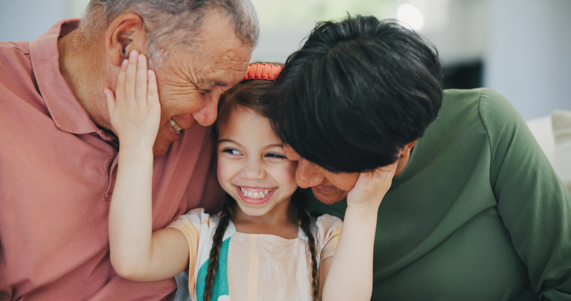 A granddaughter smiles and hugs her grandparents affectionately.