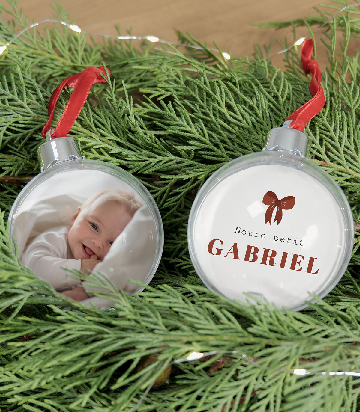 Boule de Noël personnalisée "Petit Bout" avec photo de bébé et prénom surmonté d'un nœud rouge