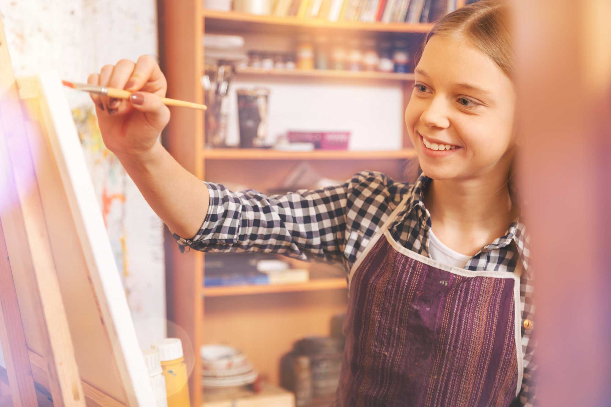  A happy child painting a picture on an easel.